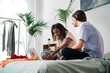 © Studio Marmellata/Stocksy - Smiling diverse female friends sharing laptop on bed