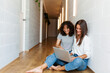 © Valentina Barreto/Stocksy - Women sharing laptop on the hall floor