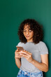 © Valentina Barreto/Stocksy - 30s woman checking phone front green wall