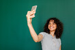 © Valentina Barreto/Stocksy - Cheerful woman taking selfies front green wall