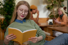 Focused Female Reading Book In Cafeteria