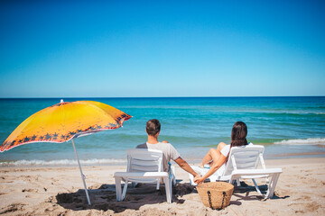 Wall Mural - Young couple in love on the beach summer vacation. Happy man and woman look at the sea 