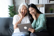 © Parichat - Young woman with mother using laptop at home, happy family time..