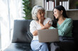 © Parichat - Young woman with mother using laptop at home, happy family time..