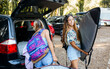 © Marco Govel/Stocksy - Female surfers taking belongings from car trunk