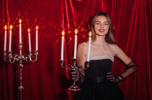 Smiling Woman Posing With Chandelier By Red Velvet Background