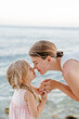 © Sergey Narevskih/Stocksy - Mother and daughter nuzzling noses on beach