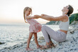© Sergey Narevskih/Stocksy - Mother with child enjoying evening playing together on beach