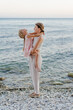 © Sergey Narevskih/Stocksy - Woman holding child on hands on seashore
