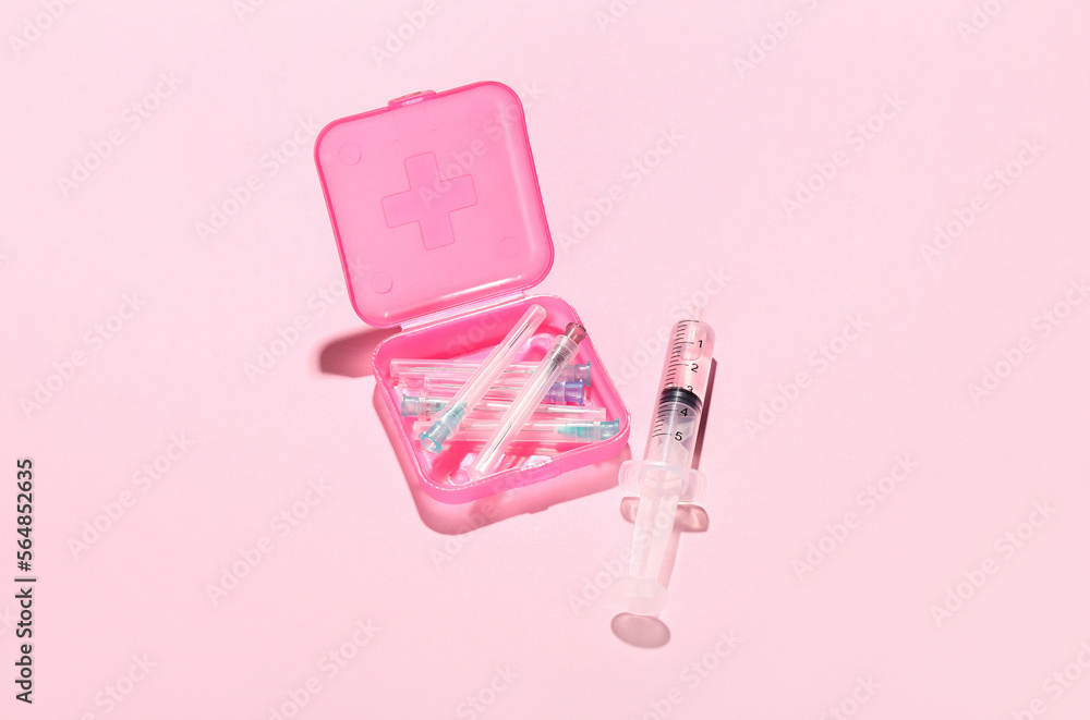 Medical syringe with remedy, container and needles on pink background
