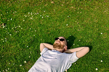 Young Man Lies On Green Grass With Wildflowers