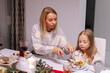 © Oleksii Syrotkin/Stocksy - Mother help  cut  meal daughter Christmas dinner