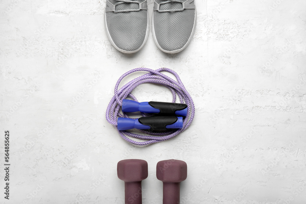Skipping rope with sneakers and dumbbells on white background