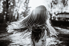 Young Girl Swinging Long Hair In Backlight