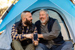 © McKinsey Jordan/Stocksy - Gay Couple Look At A Phone While Sitting In Tent