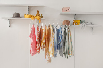 Wall Mural - Rack with striped clothes, shelves and accessories on light wall