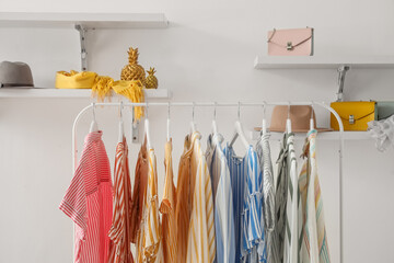 Wall Mural - Rack with striped clothes, shelves and accessories on light wall