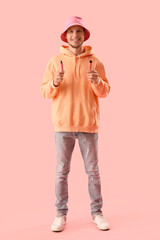 Wall Mural - Young man in bucket hat with disposable electronic cigarettes on pink background