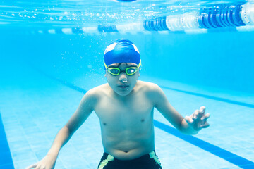 Wall Mural - latin child boy swimmer wearing cap and goggles in a swimming underwater training In the Pool in Mexico Latin America	