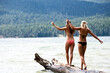© Cavan Images - Two young women balance on a log on a sunny day next to a lake in Idaho.