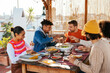 © BONNINSTUDIO/Stocksy - Cheerful diverse friends having dinner in a rooftop