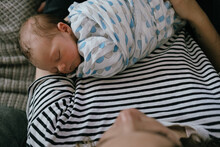 Newborn Baby Boy Sleeping In Mothers Arms.