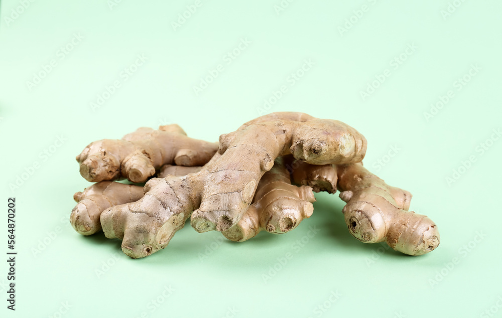 Fresh ginger roots on green background