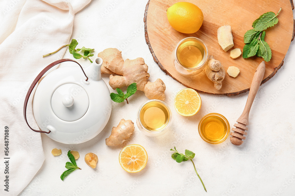 Composition with teapot, cup of tea, ginger, honey and lemon on light background