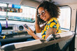 © Daniel Gonzalez/Stocksy - An afro woman inside a taxi with a phone
