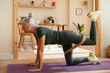 © BONNINSTUDIO/Stocksy - Senior woman with grey hair doing fitness exercise at home