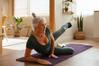 © BONNINSTUDIO/Stocksy - Mature woman doing leg rise exercise on purple mat