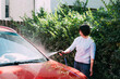 © ZQZ Studio/Stocksy - Young woman washing a red car