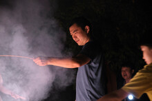 Asian Family, Having Fun With Fireworks Outdoors At Night In Nature
