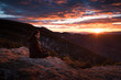 © Ibai Acevedo/Stocksy - Woman sitting on the mountain during striking sunset