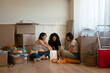 © BONNINSTUDIO/Stocksy - Female flatmates resting near carton boxes in new apartment