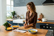 © Momento Estudio/Stocksy - senior woman with curly hair smiles while preparing a recipe