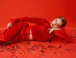 © Elenka Kharichka/Stocksy - A fashionable model in a red outfit lies on the floor with confetti