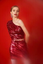 A Woman In Sequins Poses On A Red Background