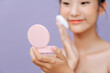 © Marc Tran/Stocksy - Beautiful young asian woman applying powder puff on cheek makeup