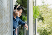 Man Listening Music And Using Mobile Phone By Building Outdoors