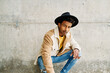 © nomad studio/Stocksy - Stylish man posing against a concrete wall.