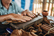 © Daniel Gonzalez/Stocksy - Man making cigar from tobacco leaves