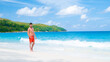 Young men in a swim short at Anse Lazio beach with turquoise colored ocean Praslin Seychelles Islands on a sunny day