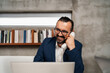 © Aleksandra Jankovic/Stocksy - Smiling Businessman Working At The Desk And Using A Landline Phone