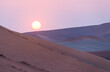 © Elena Saurius & Dani Rex/Stocksy - Sand dunes in front of the sun at sunset in Namibia, Africa.