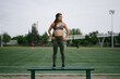 © Bianca Beltran/Stocksy - Sporty Latina woman standing on a bench in a confident posture.