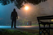 © Dave Wall/Stocksy - A hooded figure silhouetted in a park at night