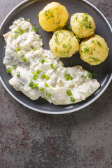 German food Sahnehering Herring fillet in creamy sauce with boiled potato garnish close-up in a plate on the table. vertical top view from above