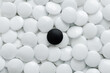 © Jeongho Byeon/Stocksy - One black Go stones and many white Go stones.