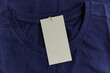 © Anna Tabakova/Stocksy - Blank  clothing label attached to blue tshirt